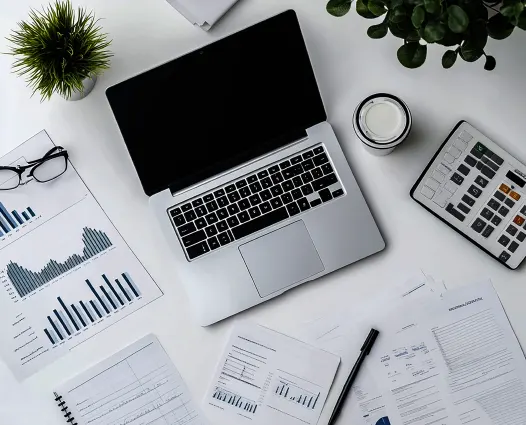 A high-angle, top-down view of a clean desk with a laptop, calculator, and financial spreadsheets, showcasing the organized approach of an Outsourced Accounting Firm in Virginia.