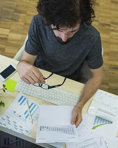 Top-down view of a financial specialist reviewing data reports and bar graphs, highlighting the detail-oriented nature of startups receivable services.