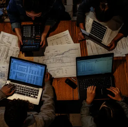 Team collaboration on tax management tasks for startups with laptops, calculators, and financial documents on the table.
