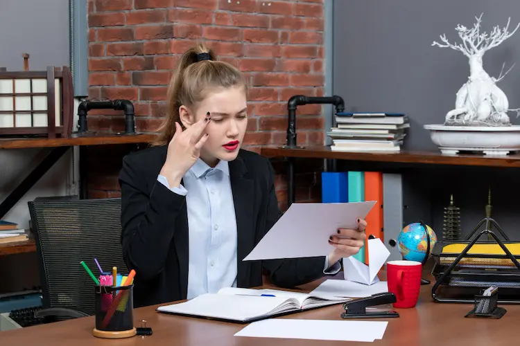 A woman in an office closely analyzing data sheets to troubleshoot and optimize ecommerce KPIs for an online store.