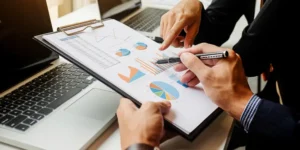 Two business partners analyzing a financial clipboard to demonstrate how the benefits of outsourcing bookkeeping improve financial clarity.