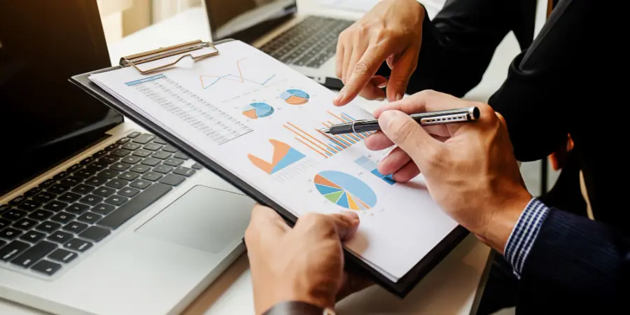 Two business partners analyzing a financial clipboard to demonstrate how the benefits of outsourcing bookkeeping improve financial clarity.