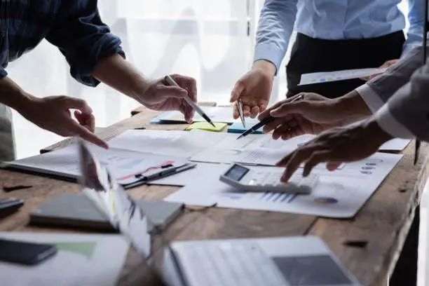 A close-up of financial professionals pointing at documents and using a calculator to analyze succession planning for financial advisors.