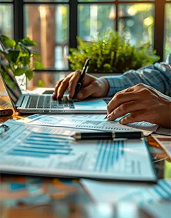 Close-up of hands analyzing financial charts and reports, representing outsource CPA services for startup bookkeeping and reporting.
