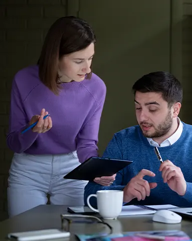 Startup payroll advisors reviewing data on a tablet while discussing payroll services for startups.