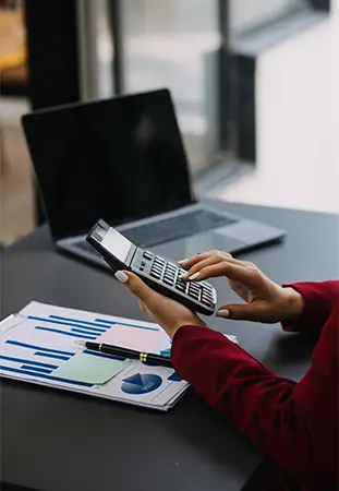 Accountant calculating employee wages with reports and laptop showing low cost payroll services in New York