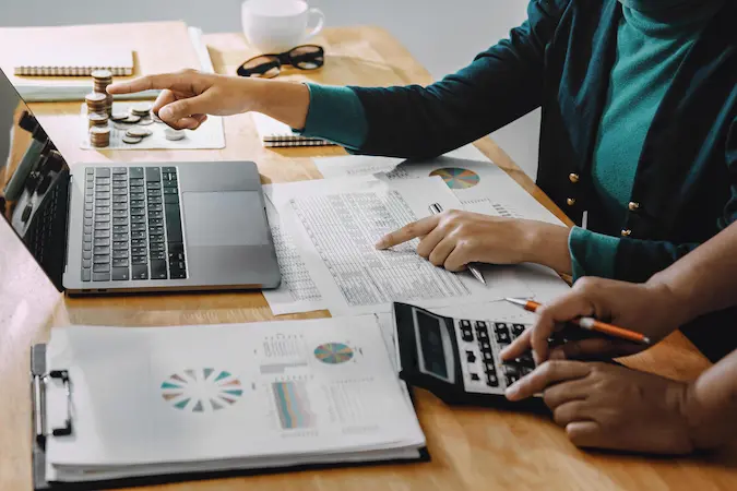A professional bookkeeper managing financial records using a laptop, calculator, and data charts to track business expenses