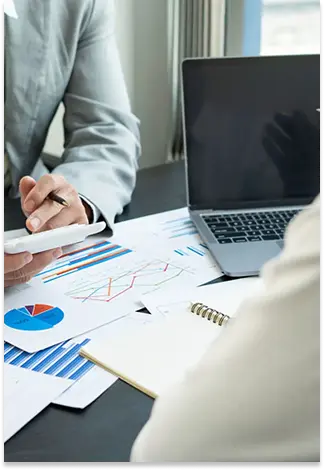 Business professional reviewing financial reports and performance charts during a client meeting.