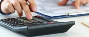 Person using a calculator to calculate payroll deductions
