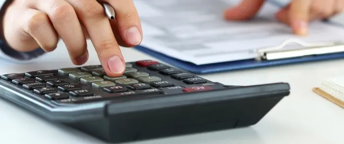 Person using a calculator to calculate payroll deductions